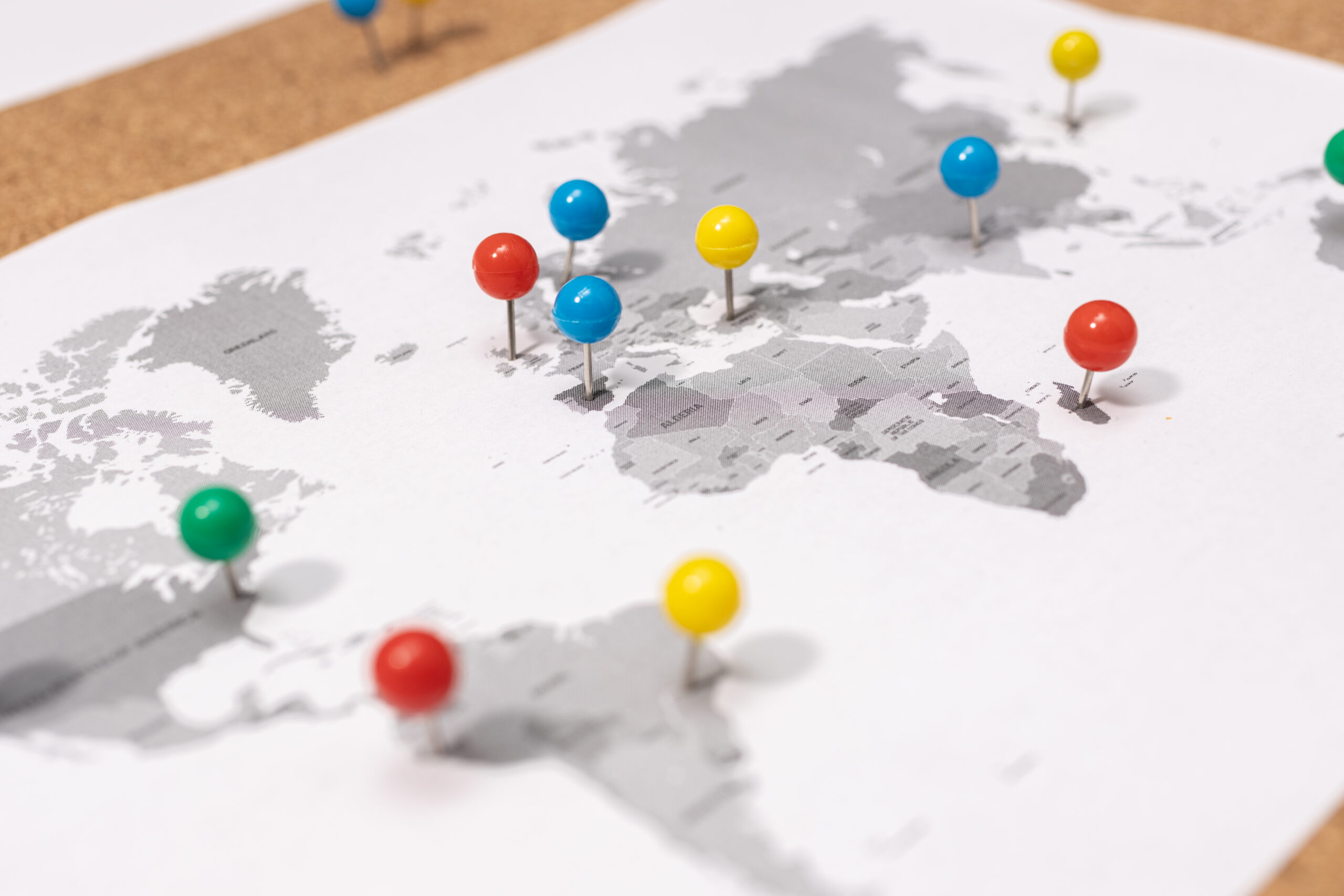 Close up of Pushpins on world map on Corkboard. Travel destination concept
